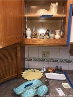 Countertop with various plates including California pottery turquoise leaf-shaped plate, yellow leaf-shaped plate, Italian rectangular plate, Japanese salt and pepper shakers