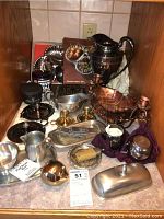 Full overview of metal ware lot including copper water pitcher, triple shell serving dish, pewter creamer and sugar, brass candlesticks, silver plate items.