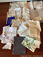 Collection of various table linens including white and cream pieces with floral embroidery, and a polka dot fabric.