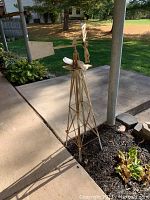 Photo showing full view of rusty metal windmill on patio near garden bed.