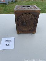 Front angled view of antique 1897 metal safe showing embossed door dial and safe body.