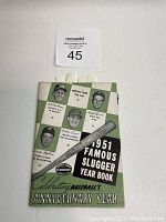 Front cover showing green and white checkered design with portraits of baseball players and a baseball bat illustration, title text '1951 Famous Sluggers Year Book' and indication of baseball's anniversary year.