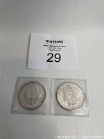 Obverse side showing Liberty profiles on two Morgan Silver Dollars dated 1882 and 1889 in protective holders.