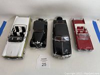 Top view of four collectible model cars arranged in a row showing detailed interiors and varying colors.