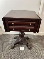Full view of antique mahogany side table with two drawers and ball and claw footed pedestal base.
