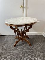 Full view of the antique marble top oval table showing marble surface and wooden carved base