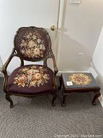 Full front view showing entire upholstered antique chair with carved wooden frame and matching ottoman with floral upholstery.