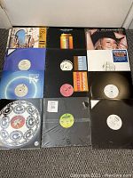 Top view showing 10 vinyl records laid out on carpeted floor including featured artists' cover art and labels.