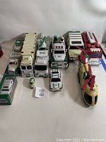 Photo showing all Hess collectible trucks and helicopter arranged in rows on a white surface.