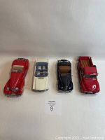 Four Danbury Mint 1/24 scale model cars shown from front and top, showcasing varied colors and styles in used condition.