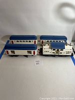 Three-piece set arranged side by side on white background showing locomotive and two cars