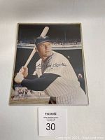 Signed color photograph of Mickey Mantle holding bat in protective plastic sleeve, lot number card '30' visible