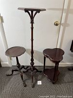 Photo showing all three vintage wooden side tables and stands with dark wood finish placed against a wall and door on carpeted floor.