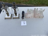 Two vintage candlesticks, small black glass horse figurine, and frosted glass angel bookends shown together on table.