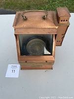 Front view of the copper lantern case with the compass visible through the glass window. The lantern has a top handle and shows the compass dial inside.