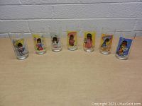 Photo showing the entire set of 7 vintage DeGrazia collectible drinking glasses, each with unique colorful illustrations of Native American children.