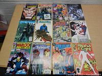 Top down view of 12 assorted comic books laid out on a table showing front covers