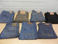 Seven pairs of Levi's jeans folded and laid out on a table against a white background showing back pockets and brand labels.