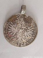 Front side showing double-headed eagle and heraldic shield with inscription, detail of soldered loop attached to edge of coin