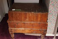 Front view of the antique wood butcher block showing the thick top and wooden legs.