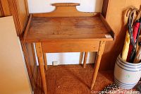 Front view of the antique wood washstand table showing the top surface, turned legs, and backsplash with turned support bar.