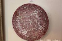 Front view of decorative Asian plate showing detailed swirling red pattern with white floral designs.