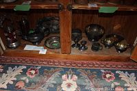 Wide view of the wooden cabinet interior showing the entire lot of silverplate items including pickle castors, teapot, plates, platters, creamer set, candlesticks, and tongs.