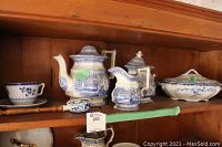 Shelf display of assorted Spode, Wedgwood, Corsina china including teapot, creamer, sugar bowl, serving dish, teacups and saucers