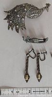 Large peacock brooch, small pin, and dangle earrings shown together with ruler for size measurement.