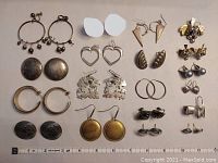 Overview photo showing the full collection of sterling silver earrings arranged in rows on a flat surface with a ruler for scale. Includes various styles such as hoops, studs, dangles, and clips as well as the brooch and opal studs.