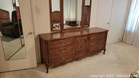 Front view of wooden triple dresser with tri-fold mirror attached