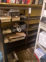 Front view of metal shelving unit filled with miscellaneous items, showing overall structure and condition.