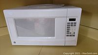 White HP countertop microwave oven on shelf, showing keypad and door