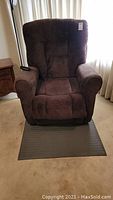 Front view of the brown upholstered recliner chair showing padded armrests and backrest.
