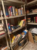 Four-tier gray plastic storage shelf unit with books on shelves (not included). Photo shows general condition and structure.