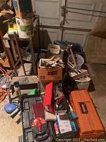 Photo shows assorted tools, hand clamps, scrapers, and toolboxes stacked in a garage setting. Items appear worn dusty and rusty.