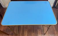 Full view of the rectangular baby blue Formica card table top and gold anodized aluminum frame