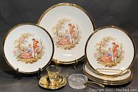 Full set viewed from front: six porcelain plates, glass/brass demitasse teacup and saucer, miniature frying pan, and small glass ashtray.