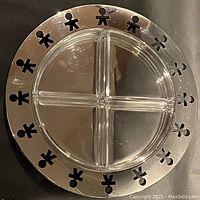 Top-down view of the assembled hors-d’oeuvre serving dish showing mirrored stainless steel outer edge with stylized human figure cut-outs and four clear glass section inserts.