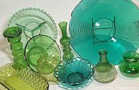 Assortment of green glassware items including vases, bowls, candleholders, and a divided serving dish.