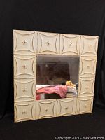 Front view of a square mirror with a decorative painted tin metal frame showing embossed patterns.