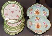 Stack of four Vienna Austrian floral plates beside two Meissen shell bowls on black background