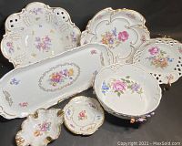 Full view of all seven porcelain floral chinaware items on black surface