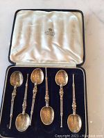 Six ornate spoons arranged in navy velvet tray of black leather presentation case