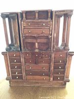 Full front view of the vintage wooden display cabinet showing the overall structure with central drawers and flanking open compartments with wooden columns.