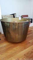 Angled side view of the large copper vessel showing its size and patina.