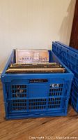 Blue plastic crate filled with vinyl records, with The Mama's and The Papa's album visible