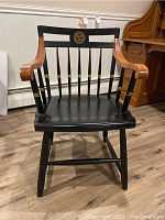 Front view of Nichols & Stone collegiate armchair painted black with gold accents, natural wood armrests, and collegiate emblem on backrest.