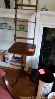Wooden tiered table with a small square top and tall vertical frame with horizontal bars