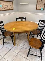 Oval butcher block table with four wooden chairs around it, showing overall look and seating arrangement.